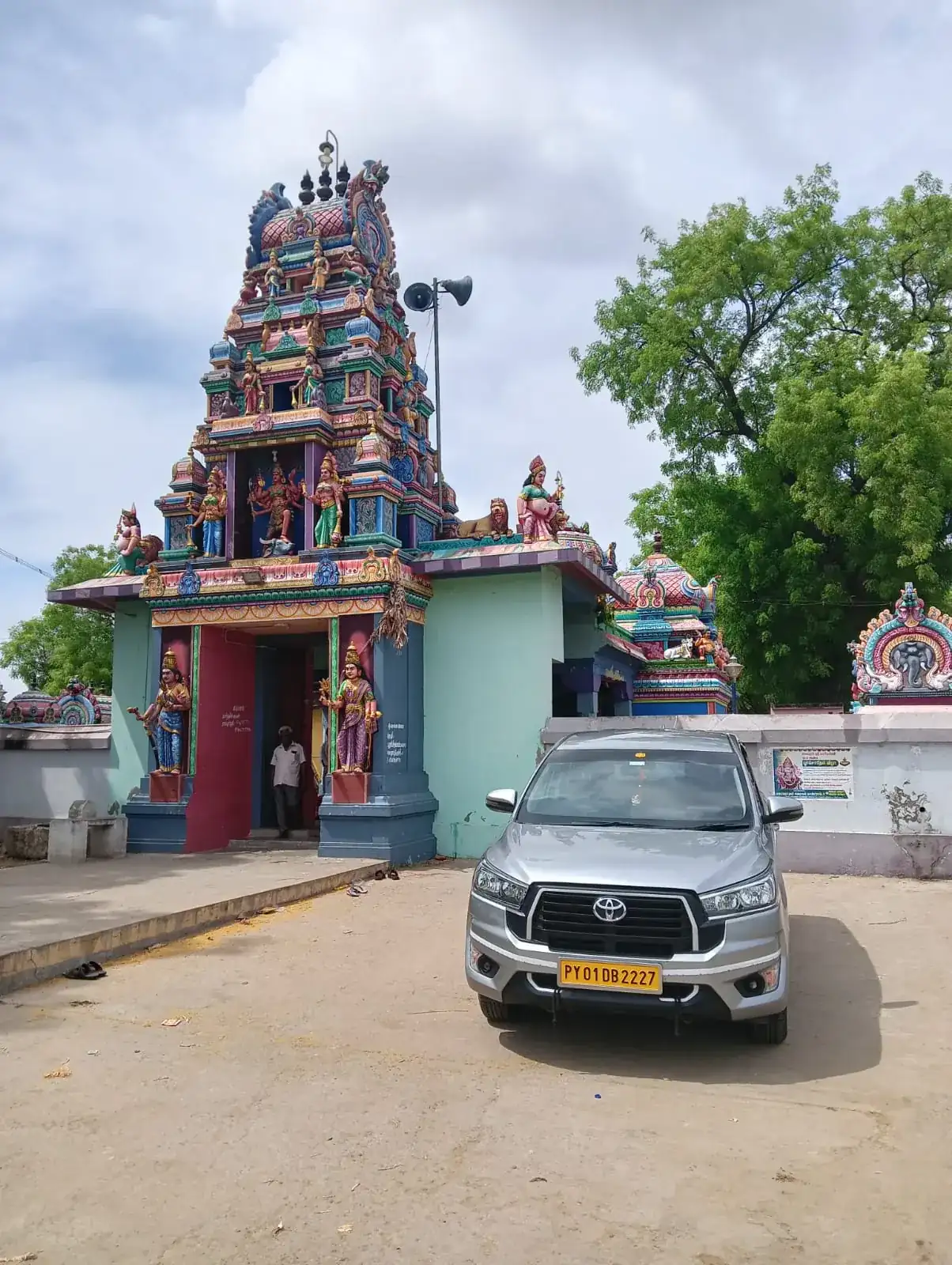 Silver Innova Crysta parked in front of a colourful temple gopuram