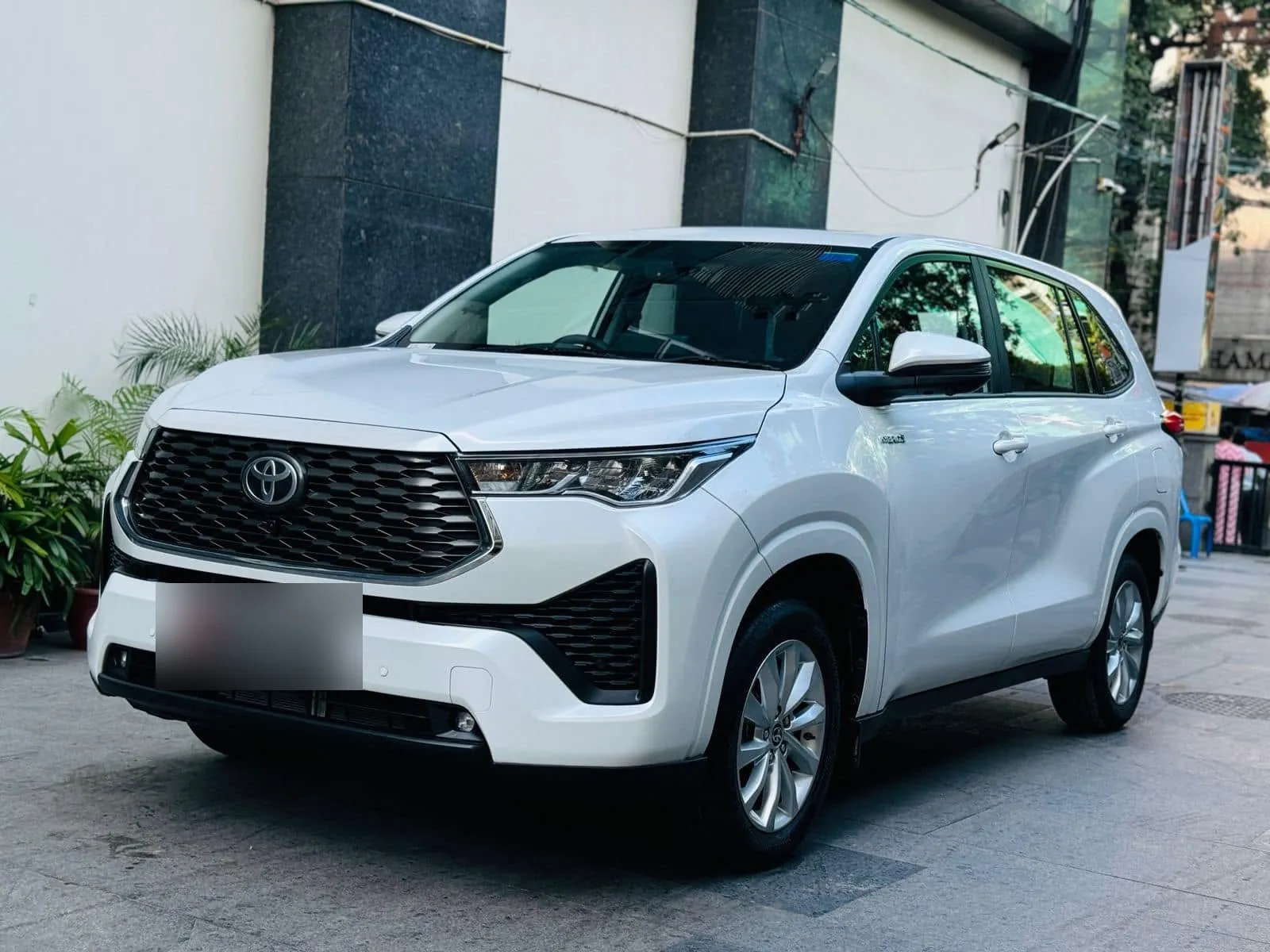 White Toyota Innova Hycross three-quarter front view parked outside an office building